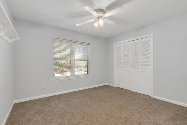 unfurnished bedroom with carpet, ceiling fan, a textured ceiling, and a closet