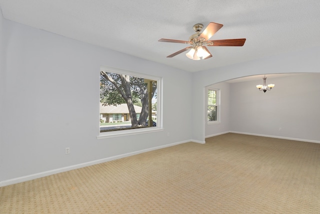 spare room featuring carpet, ceiling fan with notable chandelier, and a textured ceiling