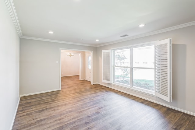 empty room featuring an inviting chandelier, wood-type flooring, and ornamental molding