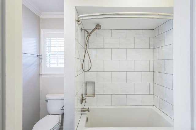 bathroom with toilet, crown molding, and tiled shower / bath