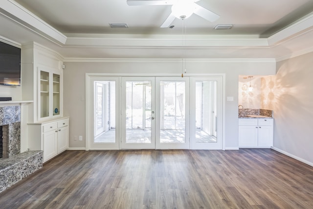 unfurnished living room with a high end fireplace, french doors, ceiling fan, crown molding, and dark wood-type flooring