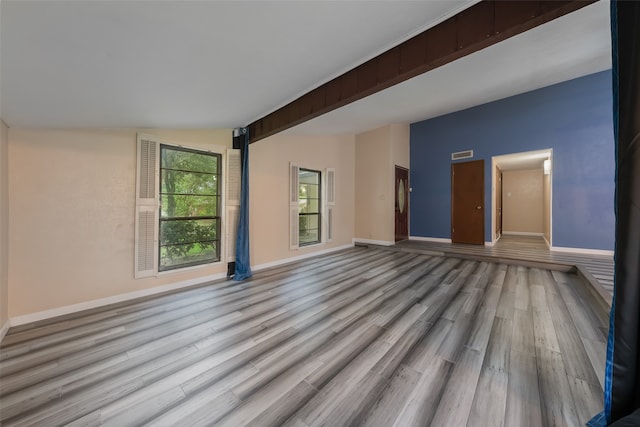 spare room with lofted ceiling with beams and light hardwood / wood-style flooring