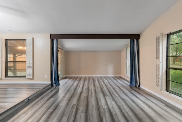 empty room featuring beam ceiling and light hardwood / wood-style flooring