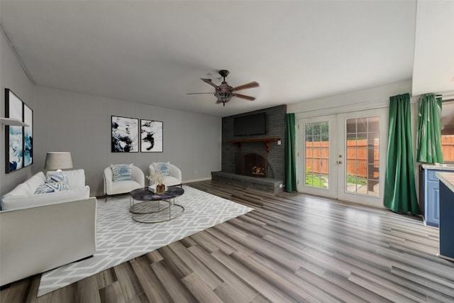 living room featuring a fireplace, french doors, light wood-type flooring, and ceiling fan