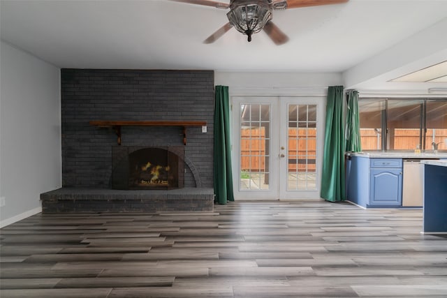 unfurnished living room with ceiling fan, french doors, light hardwood / wood-style floors, and a brick fireplace