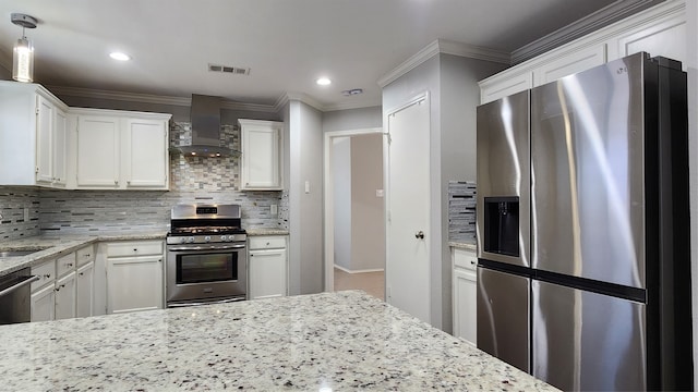 kitchen featuring white cabinets, decorative backsplash, wall chimney range hood, and appliances with stainless steel finishes