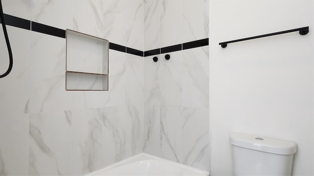 bathroom featuring tiled shower / bath combo and toilet