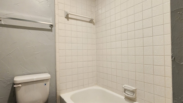 bathroom with toilet and tiled shower / bath