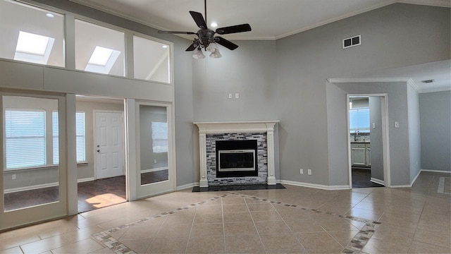 unfurnished living room featuring a skylight, ceiling fan, high vaulted ceiling, and ornamental molding