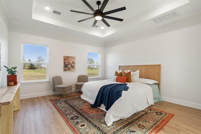 bedroom with a raised ceiling, ceiling fan, hardwood / wood-style floors, and crown molding