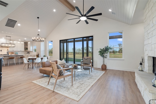 living room featuring a fireplace, ceiling fan with notable chandelier, high vaulted ceiling, and light hardwood / wood-style flooring