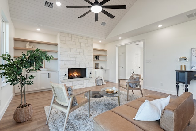 living room featuring high vaulted ceiling, ceiling fan, built in features, light wood-type flooring, and a fireplace