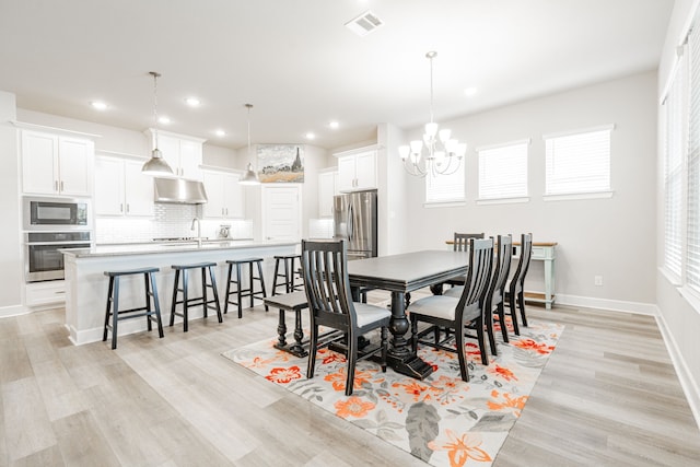 dining area featuring a notable chandelier, light wood-type flooring, and sink