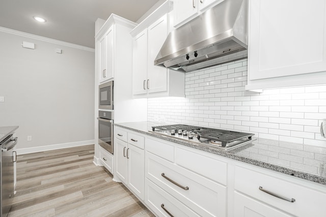 kitchen featuring white cabinetry, stainless steel appliances, light stone counters, ornamental molding, and light wood-type flooring