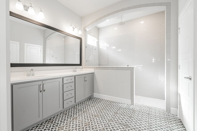 bathroom with tile patterned flooring, a tile shower, and vanity