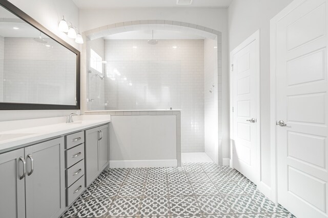 bathroom featuring tile patterned flooring, a tile shower, and vanity