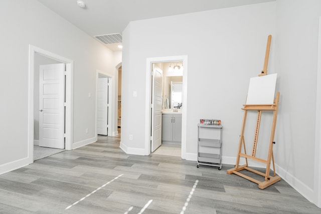 unfurnished bedroom featuring ensuite bathroom and light hardwood / wood-style floors