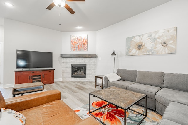 living room with ceiling fan, a fireplace, and light hardwood / wood-style flooring