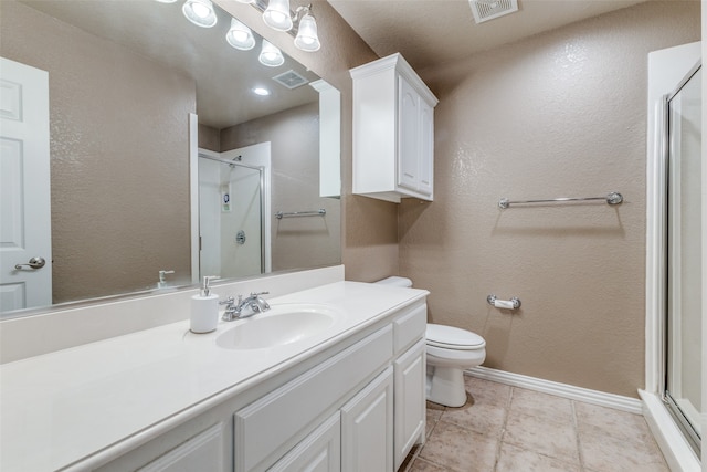 bathroom with tile patterned floors, vanity, a shower with shower door, and toilet