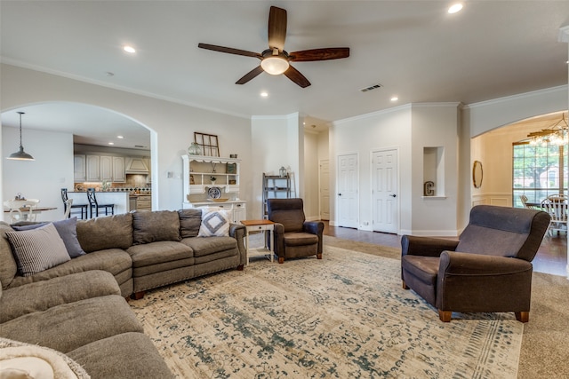 living room with ceiling fan with notable chandelier and ornamental molding