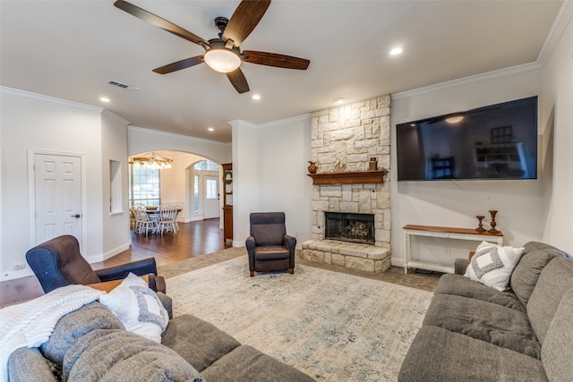 living room with hardwood / wood-style floors, ceiling fan with notable chandelier, crown molding, and a fireplace