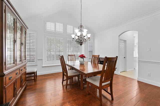 dining space with a healthy amount of sunlight, vaulted ceiling, a chandelier, and wood-type flooring