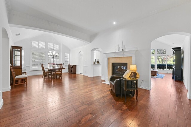 living room featuring a tiled fireplace, vaulted ceiling, dark hardwood / wood-style floors, and an inviting chandelier