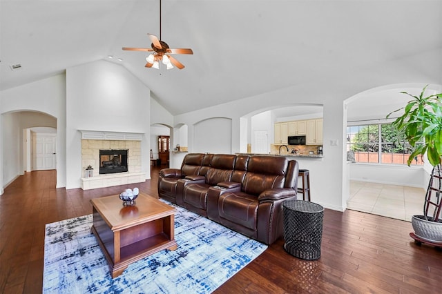 living room featuring high vaulted ceiling, ceiling fan, hardwood / wood-style floors, a fireplace, and sink