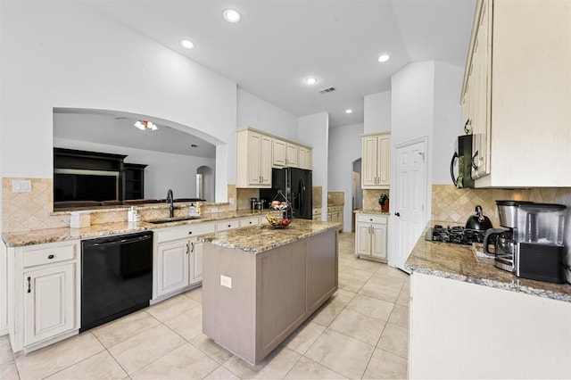 kitchen featuring light stone counters, black appliances, a center island, light tile patterned floors, and sink