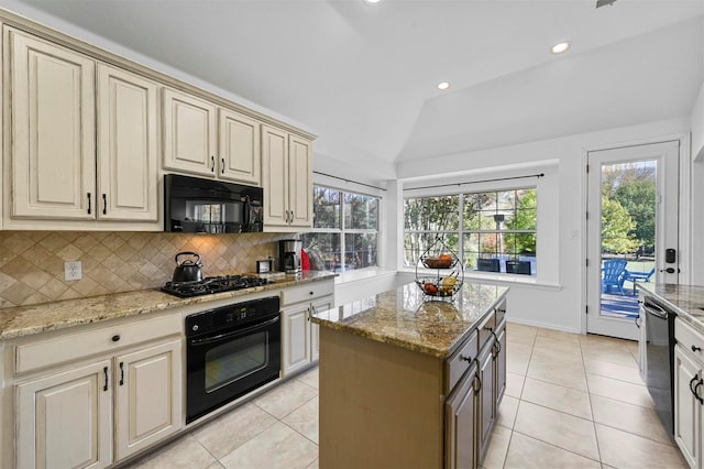 kitchen with light tile patterned floors, lofted ceiling, a kitchen island, cream cabinets, and black appliances