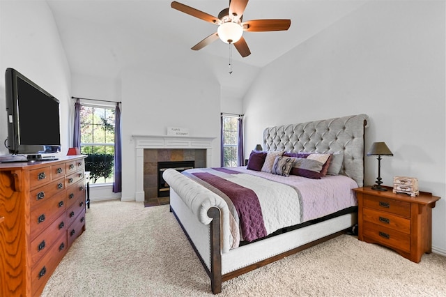 carpeted bedroom featuring ceiling fan, vaulted ceiling, and a tiled fireplace