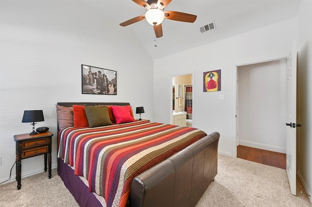 bedroom with ceiling fan, vaulted ceiling, light carpet, and connected bathroom