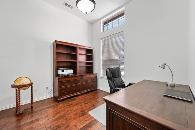 home office with dark wood-type flooring and a towering ceiling