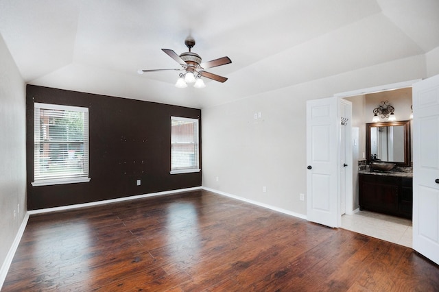 empty room with wood-type flooring, a raised ceiling, and ceiling fan