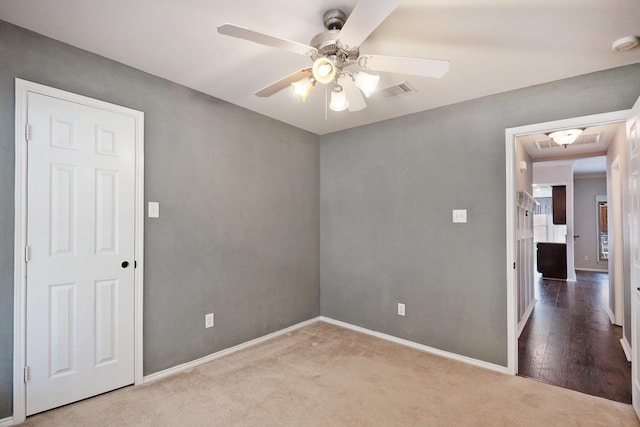 empty room with ceiling fan and light carpet