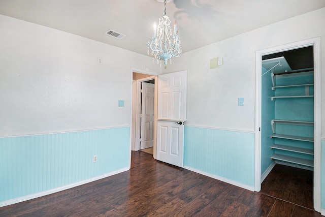 unfurnished bedroom featuring dark hardwood / wood-style flooring and a notable chandelier