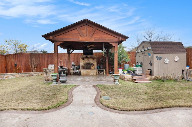 exterior space with ceiling fan, an outdoor stone fireplace, a shed, a gazebo, and a patio