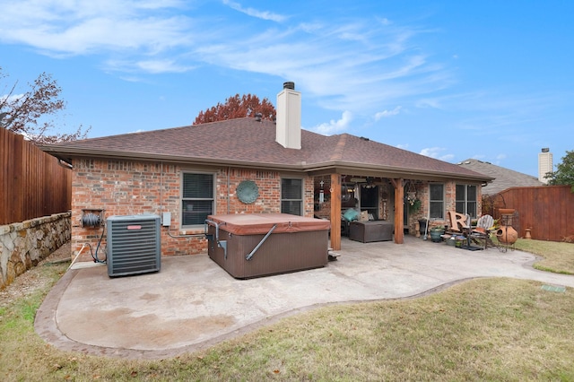 back of house with cooling unit, a yard, a hot tub, and a patio