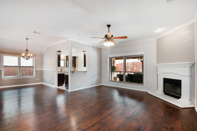 unfurnished living room with ornamental molding, plenty of natural light, dark hardwood / wood-style floors, and ceiling fan with notable chandelier