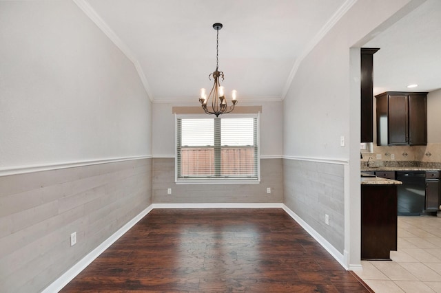 unfurnished dining area with hardwood / wood-style flooring, crown molding, and an inviting chandelier