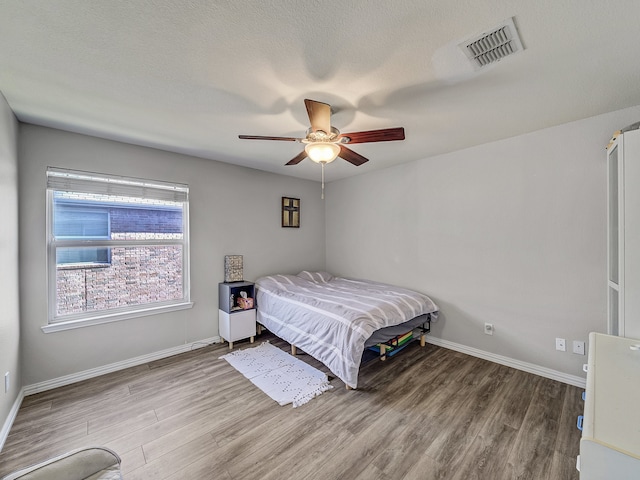 bedroom with wood-type flooring, a textured ceiling, and ceiling fan