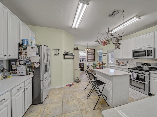 kitchen featuring appliances with stainless steel finishes, white cabinetry, pendant lighting, and a kitchen breakfast bar