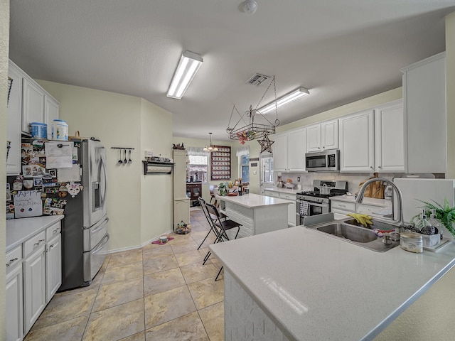 kitchen featuring a center island, stainless steel appliances, white cabinetry, and hanging light fixtures