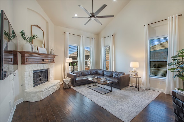 living room with a stone fireplace, ceiling fan, dark hardwood / wood-style flooring, and high vaulted ceiling