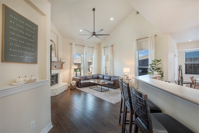 living room with ceiling fan, dark hardwood / wood-style flooring, a fireplace, and high vaulted ceiling