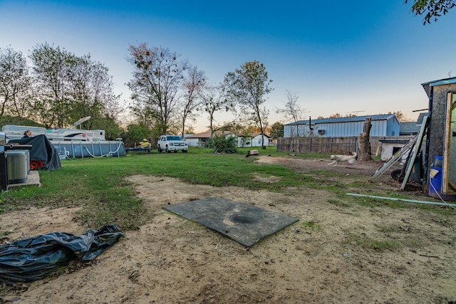 yard at dusk with central air condition unit and a swimming pool