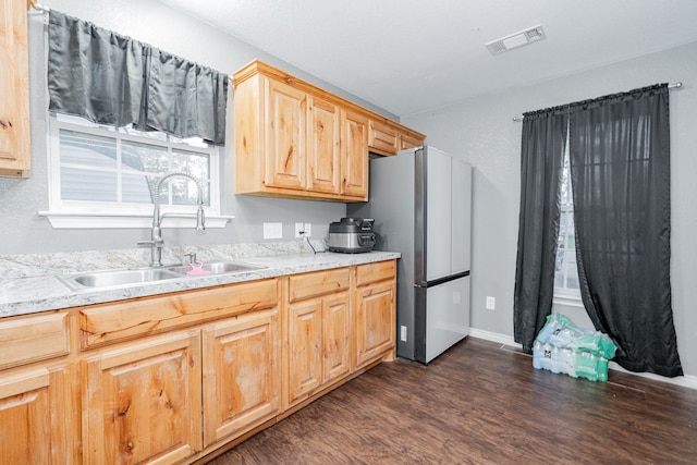 kitchen featuring light brown cabinetry, stainless steel refrigerator, dark wood-type flooring, and sink