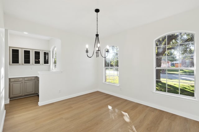 unfurnished dining area featuring light hardwood / wood-style floors, a wealth of natural light, and a chandelier