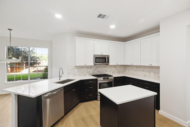 kitchen with appliances with stainless steel finishes, light wood-type flooring, tasteful backsplash, and sink