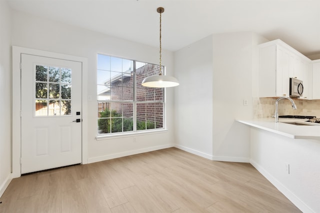 unfurnished dining area featuring light hardwood / wood-style floors, a wealth of natural light, and sink